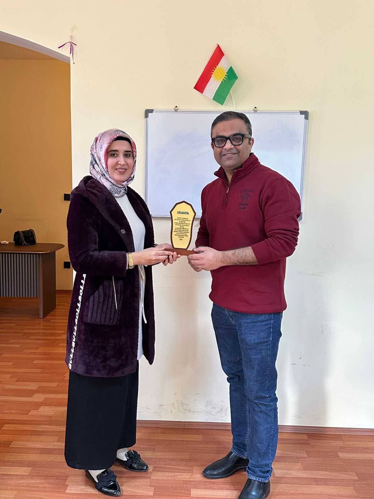 Award being presented indoors by a woman and a man.