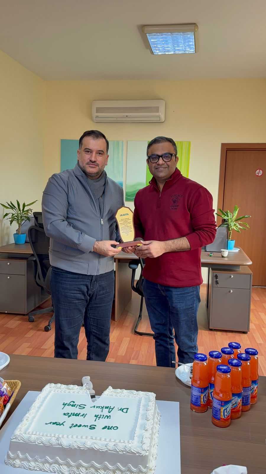 Two men holding an award plaque in an office setting.