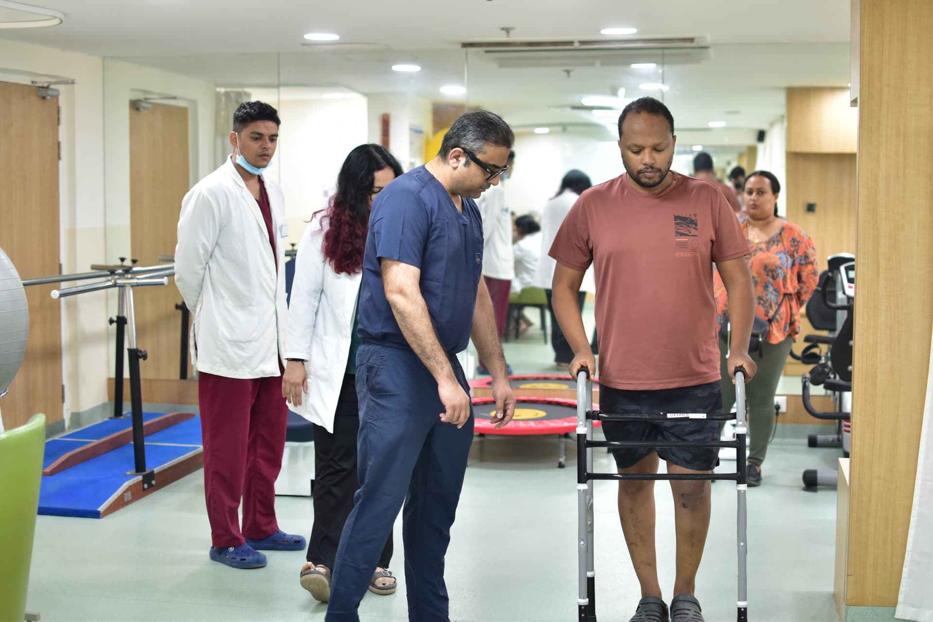 Post ACL surgery Ethiopian patient walking with walker guided by medical team